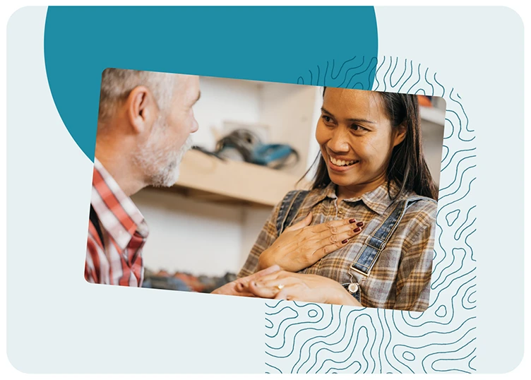 Une femme souriante pose la main sur son cœur en échangeant un moment d’écoute et de reconnaissance avec un homme plus âgé